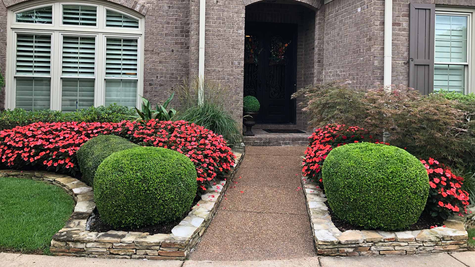 Trimmed landscape bushes and trees around a home's doorway in Memphis, TN.