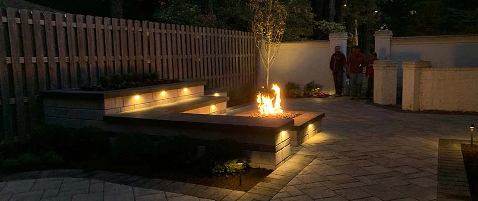A custom square firepit with seating walls installed on a patio by a home in Lakeland, TN.