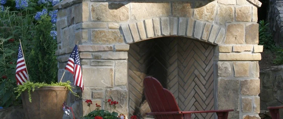Outdoor fireplace in Memphis, TN, with flags and a chair.