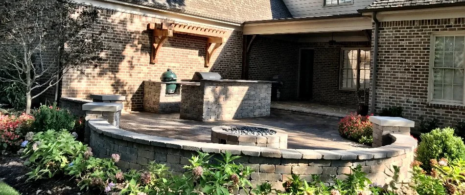 An outdoor kitchen on a patio in Memphis, TN, with a fire pit and seating wall.
