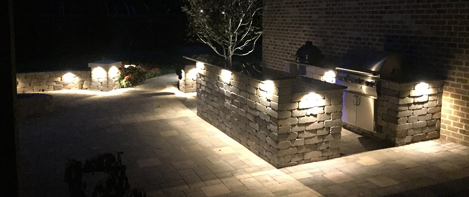A recently built outdoor kitchen lit up at night with specialized outdoor lighting in Lakeland, TN.