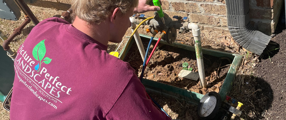 A professional performing an irrigation startup service in Memphis, TN.