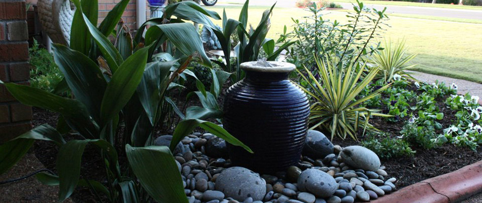 A landscape bed with a water feature in front of a home in Oakland, TN.
